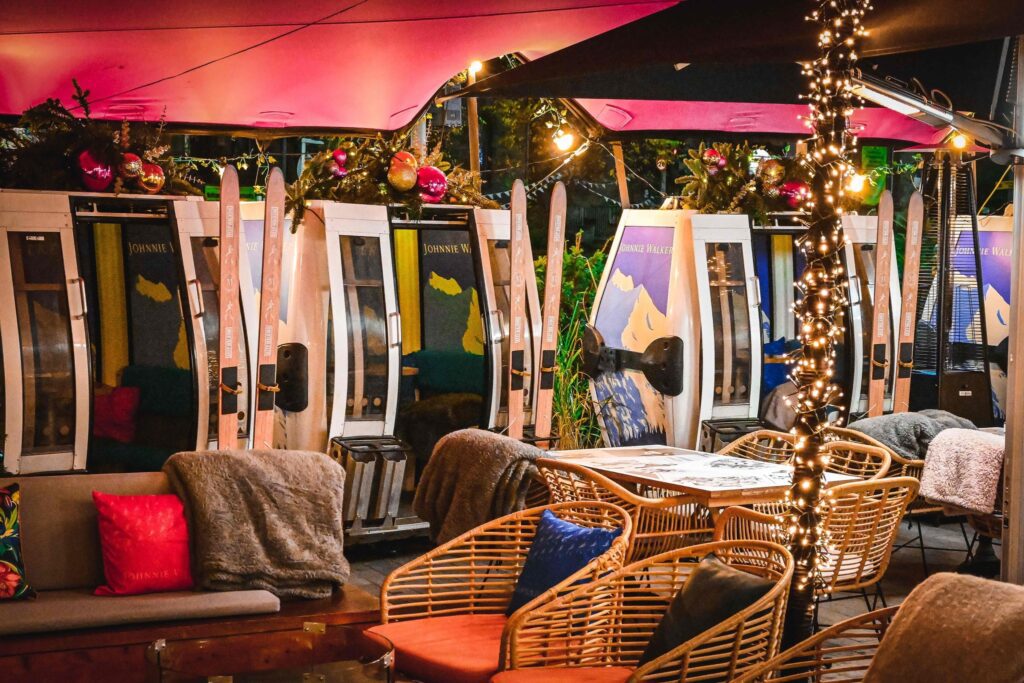 The terrace at McLarens on the Corner at night, with fairy lights lighting the seating area outside the ski gondolas. 